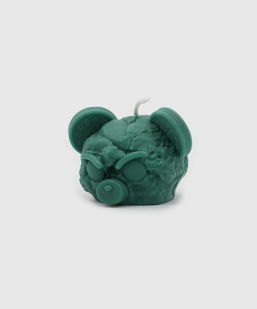Green sculpted candle in the shape of an angry bear head with cookie ears, closed eyes, and a pacifier nose – collectible home accessory from the Sucux Cool Collection.