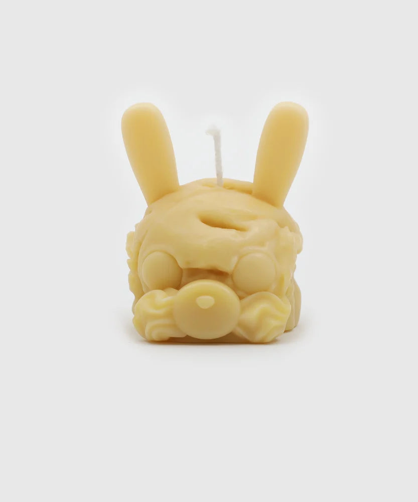 Front view of a light yellow candle shaped like a bunny head with long ears, round closed eyes, a pacifier nose, and detailed frosting-like texture – part of the Sucux Cool Collection.
