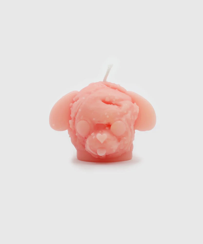 Front view of a soft pink dog-shaped candle with droopy ears, round closed eyes, and a heart-shaped nose, featuring a textured, scoop-like surface – part of the Sucux Cool Collection.