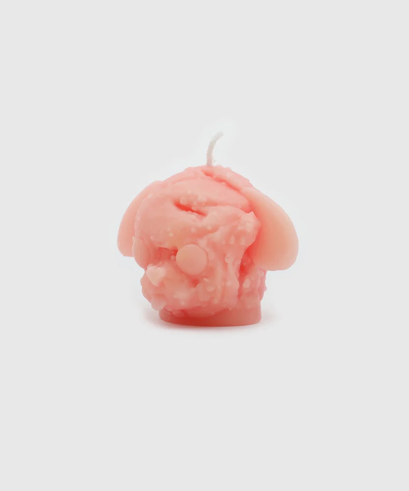 Front view of a soft pink candle shaped like a dog head with droopy ears, closed eyes, and a textured, melting ice cream-like surface – part of the Sucux Cool Collection.