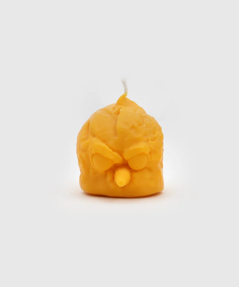 Front view of a yellow bird-shaped candle with a sharp cone beak, cartoonish angry eyes, and a sculpted texture mimicking ice cream – part of the Sucux Cool Collection.