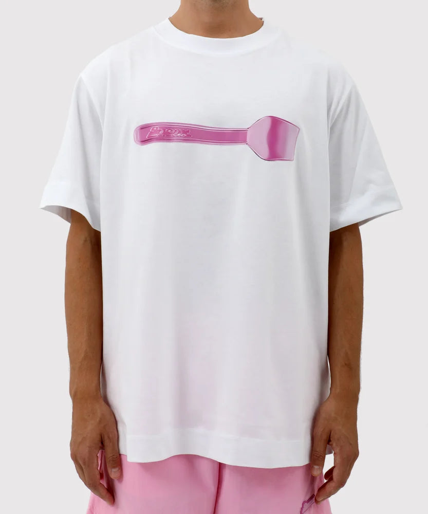 A white oversized T-shirt with a glossy pink plastic spoon graphic centered on the chest, part of the Sucux Cool Collection.