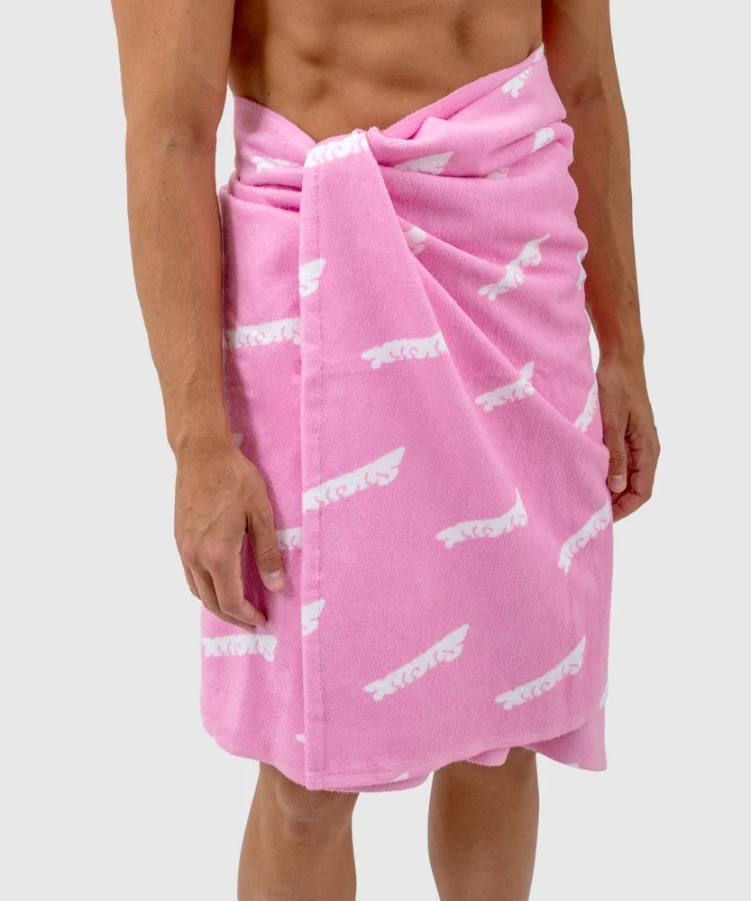 Person wearing a pink towel wrapped around the waist, featuring an all-over white Sucux logo pattern – part of the Sucux Cool Collection.