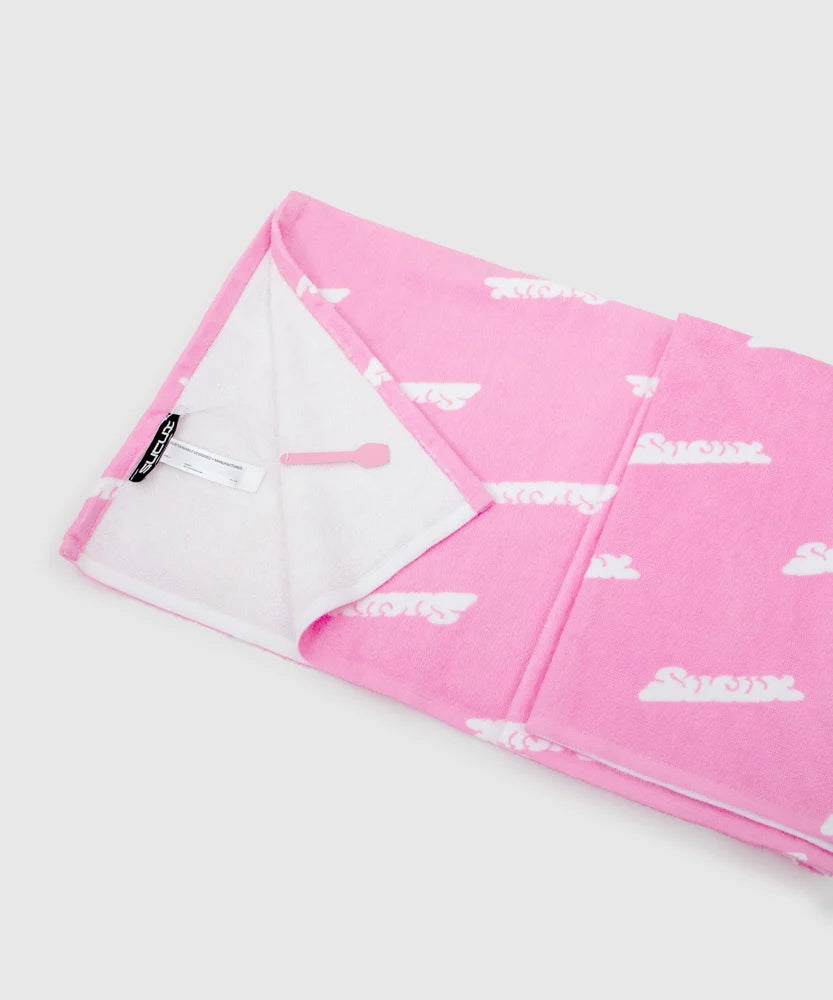 Close-up of a folded pink towel with all-over white Sucux logo print, showing white terry cloth interior, product tag, and a small pink scoop-shaped keychain – part of the Sucux Cool Collection.