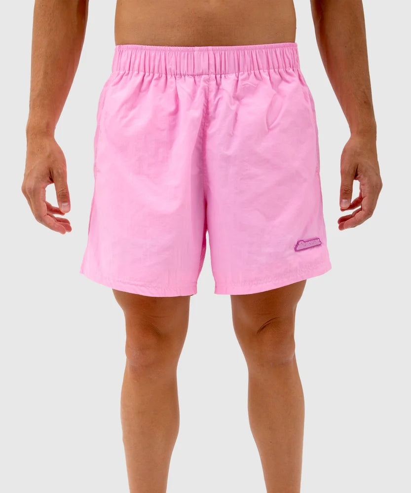 Front view of a person wearing light pink swim shorts with an elastic waistband and a small purple Sucux logo patch on the left leg – part of the Sucux Cool Collection.
