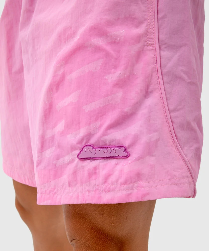 Close-up of pink swim shorts showing a hidden Sucux logo pattern becoming visible when wet, with a purple Sucux patch near the hem – part of the Sucux Cool Collection.