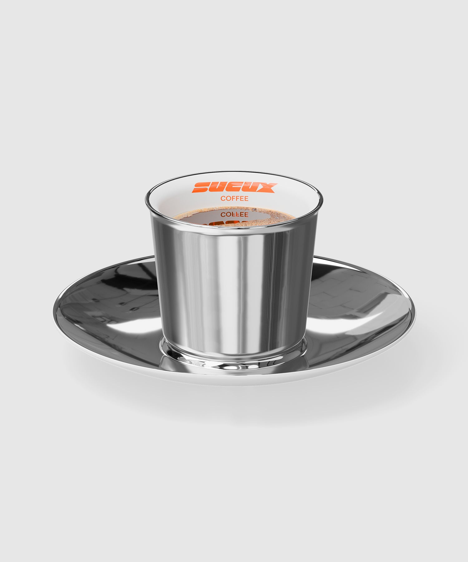 Porcelain espresso cup with a reflective chrome-like finish and matching saucer. The cup is filled with coffee and features the orange SUCUX COFFEE logo printed on the white interior rim.