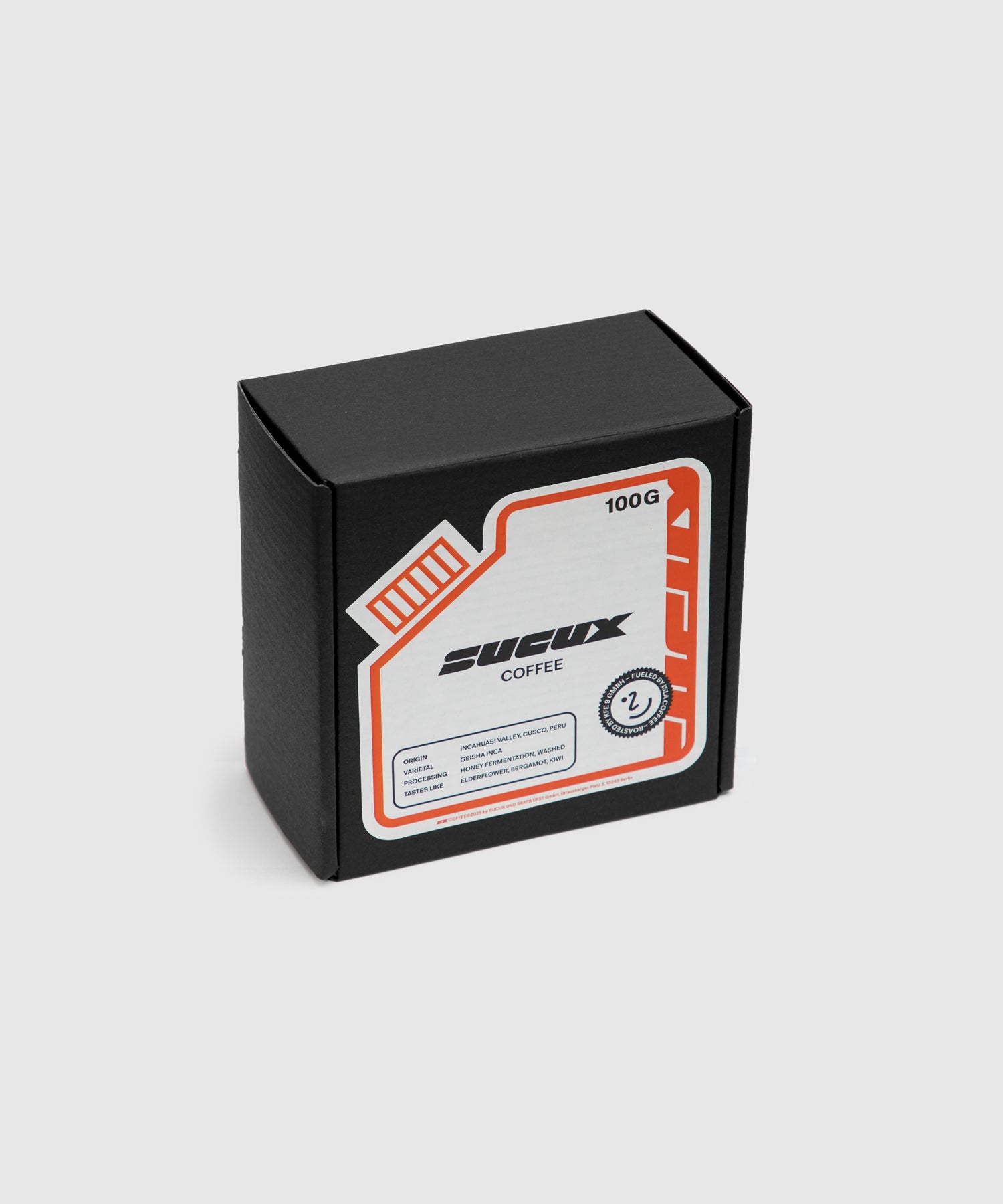 A black box of SUCUX coffee beans with a futuristic, tech-inspired label in white, orange, and black. The label displays product details including origin (Cusco, Peru), processing method (honey, washed), and flavor notes (elderflower, bergamot, wine). The box contains 100g of specialty coffee.