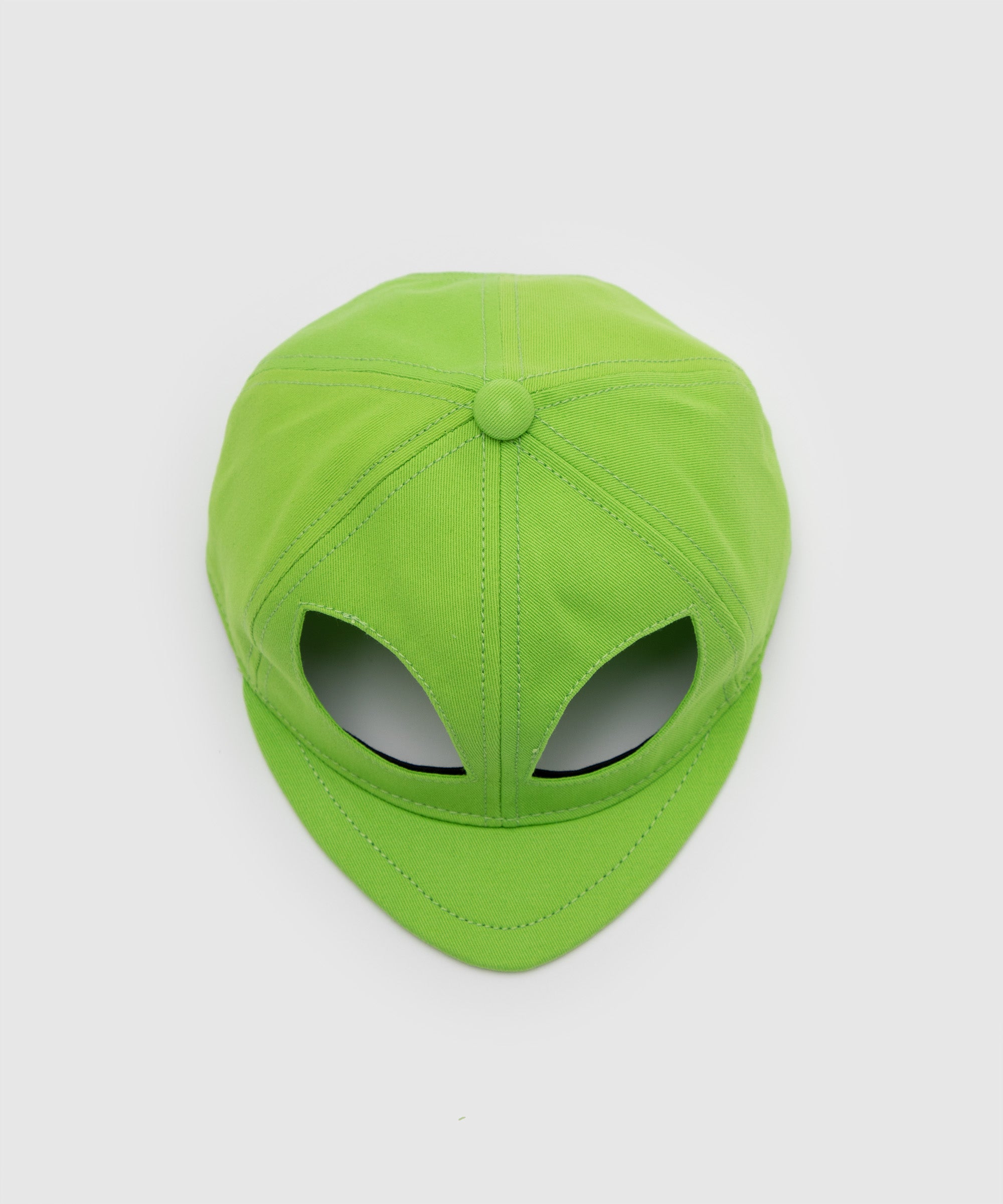 Lime green cap designed with cut-out eye shapes resembling an alien head, viewed from above – conceptual fashion piece by Sucux Lab.