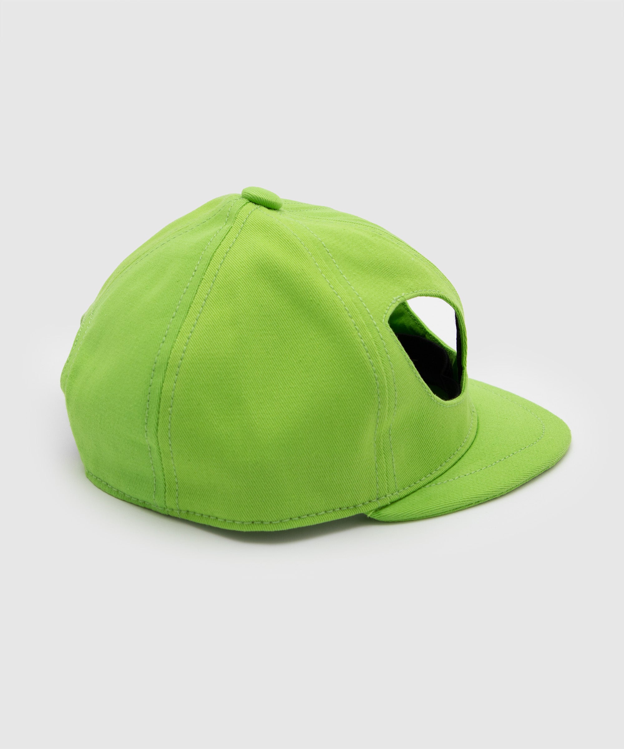 Side view of a lime green cap featuring alien eye-shaped cutouts on the front panels, shown from a rear angle – Sucux Lab x Body Holes collaboration piece.